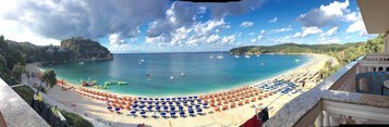 Una playa con sombrillas y barcos.