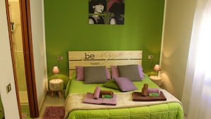 A bedroom with a green wall, a bed with a headboard that says "be happy," two nightstands with lamps, and a purple rug. - Sa Babbaiola B&B (Cagliari)