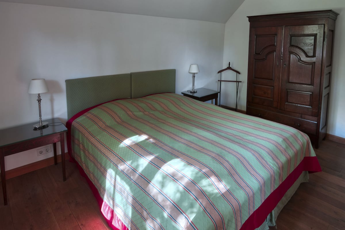 A bedroom with a bed, two bedside tables, a wardrobe, and a lamp.