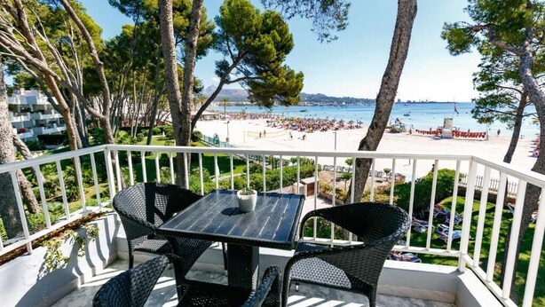 A balcony with wicker furniture overlooking a beach. - Caprice Playa de Alcudia Apartments (Alcúdia)