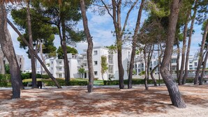 A residential area with white buildings, trees, and a sandy ground. - Caprice Playa de Alcudia Apartments (Alcúdia)