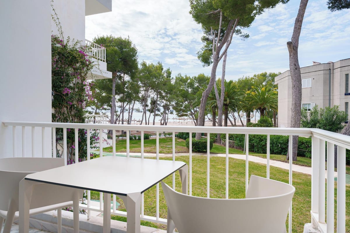Een balkon met witte hekwerken, een tafel en stoelen.