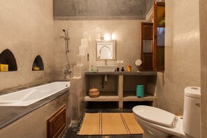 Et lille badeværelse med badekar, håndvask og toilet.