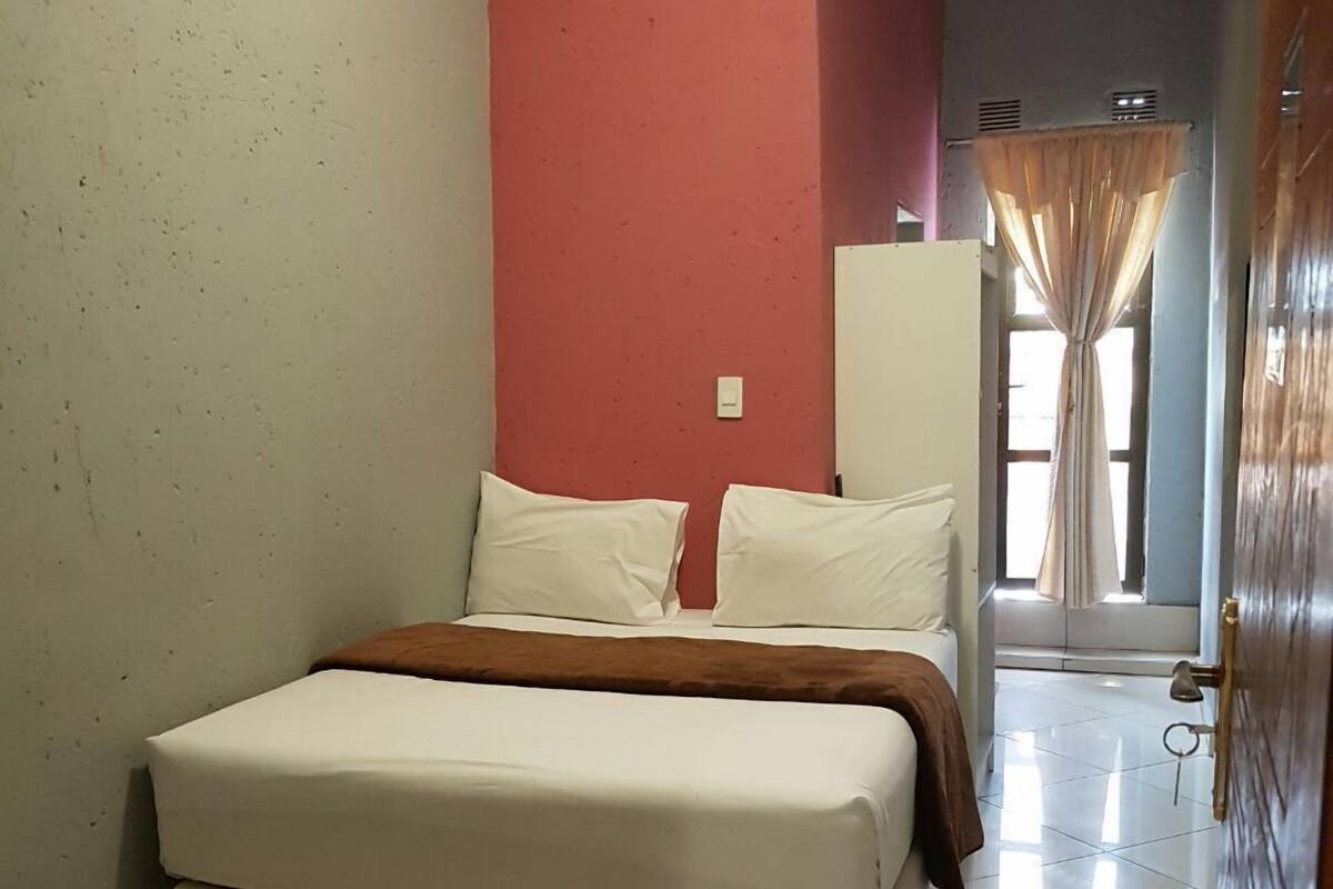 Ein Schlafzimmer mit einem Bett, einer roten Wand und einer Tür zu einem anderen Raum.