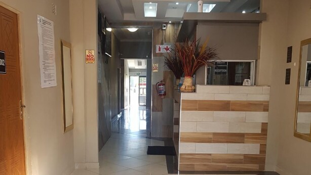 Zona de recepción de hotel con mostrador, señal de no fumar y letrero de recepción.