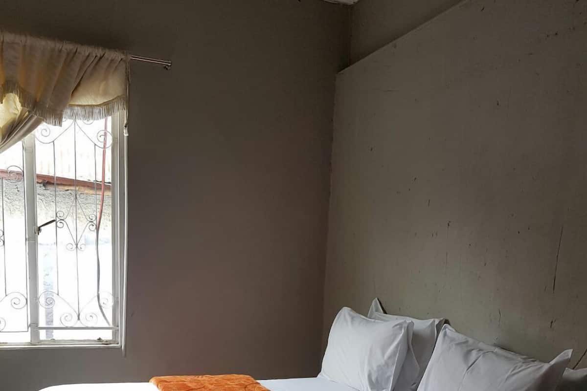 Ein Zimmer mit einem Einzelbett, einem weißen Bettgestell und einem Fenster mit Vorhängen.