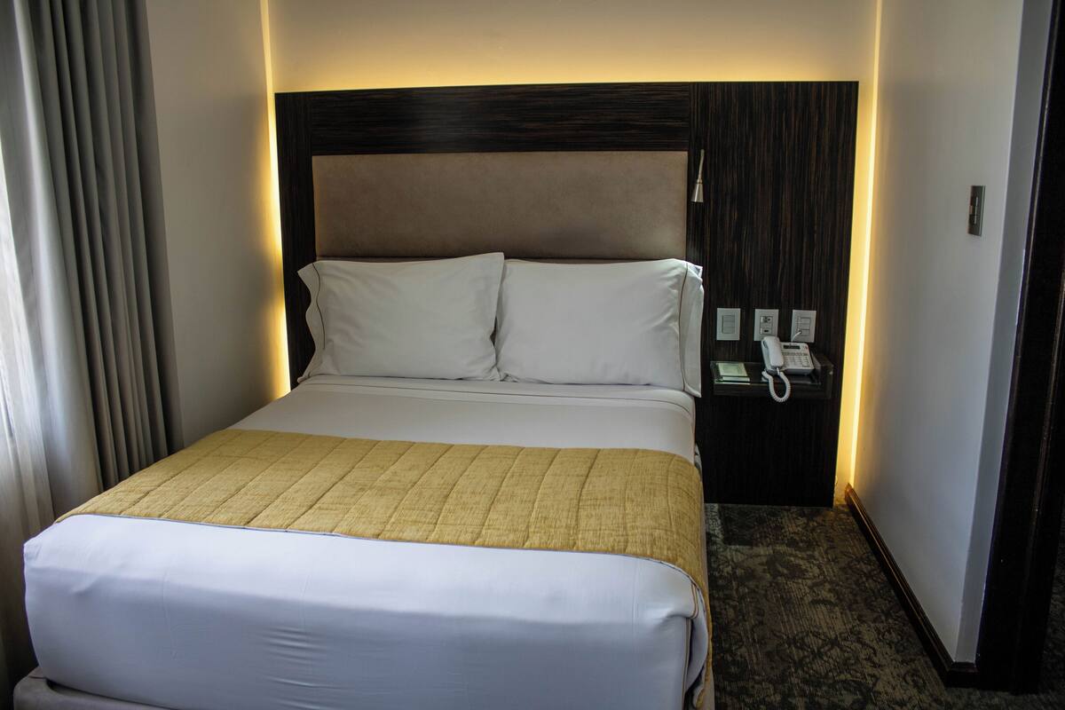 Ein Hotelzimmer mit einem großen Bett, einem Nachttisch und einem Telefon.