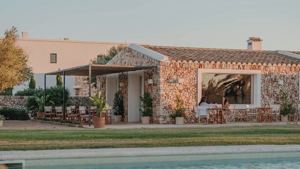 Ein Steinhaus mit Pool, Sitzgelegenheiten im Freien und einem Garten.