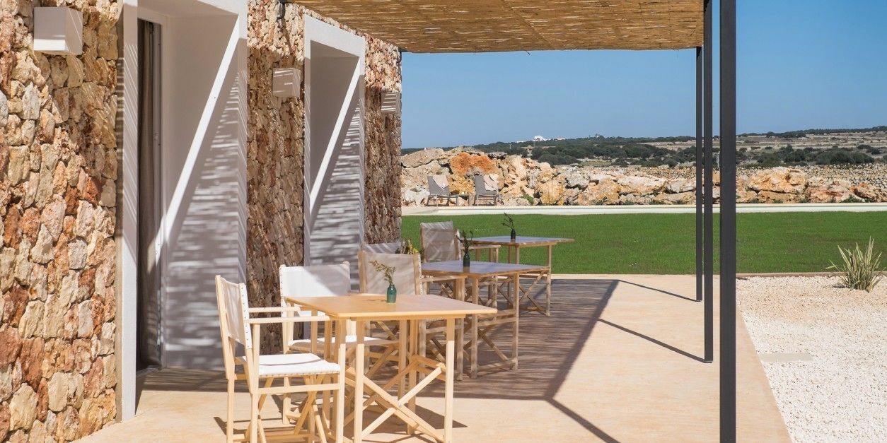 A stone building with a covered patio, outdoor seating, and a view of the sea.