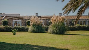 Ein Gebäude aus Stein mit einem Ziegeldach, umgeben von gepflegtem Gras und hohem Gras.