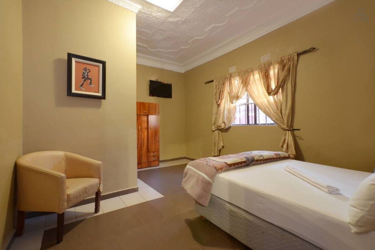 Une chambre d’hôtel avec un lit, une chaise, une armoire et un tableau encadré au mur.