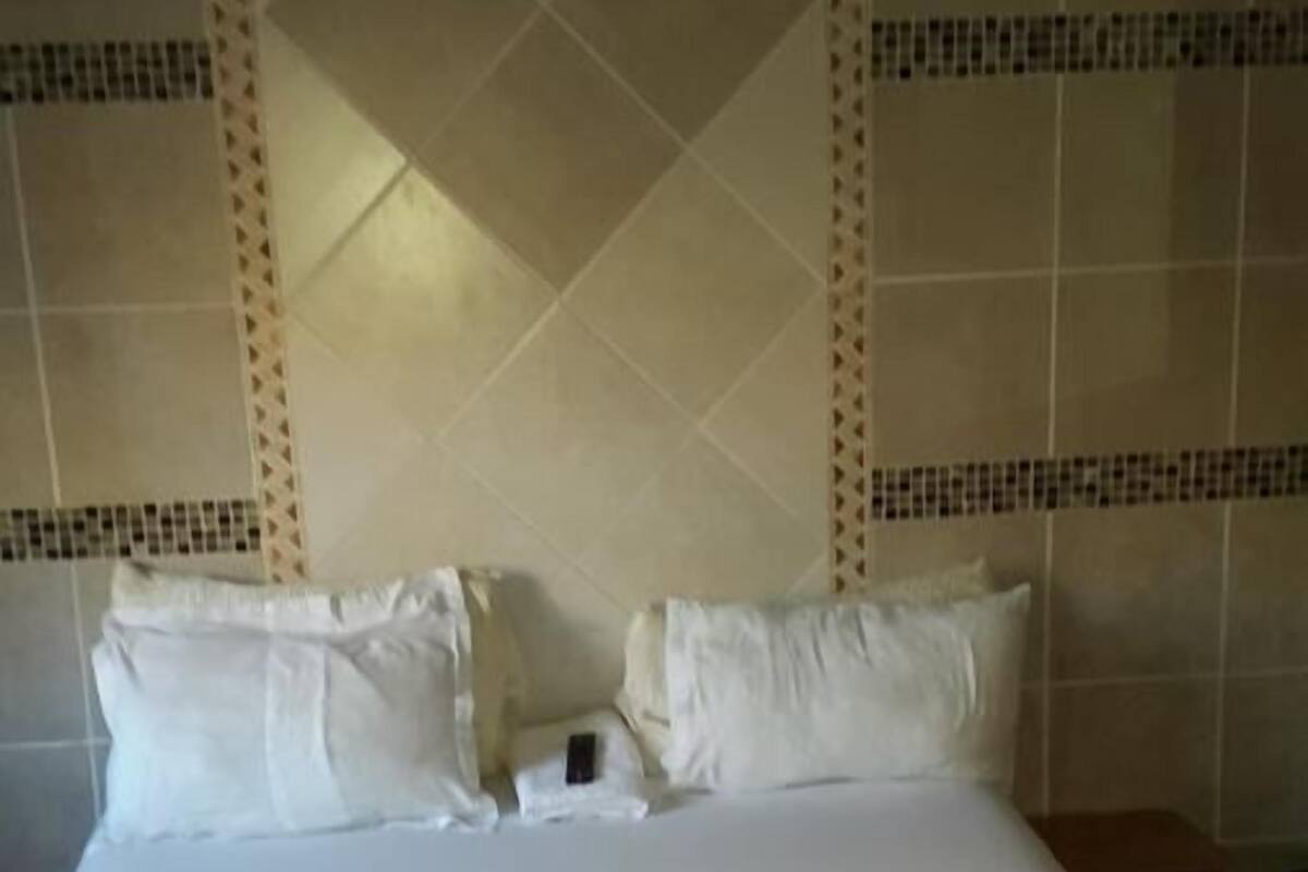 Une chambre d’hôtel avec un grand lit, du linge de lit blanc et une tête de lit décorative.