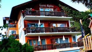 A multi-story hotel with balconies, a children's play area, and a visible sign reading "Garnier Alpha". - Alpha (Graechen)