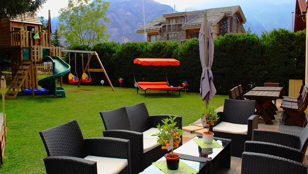 A backyard with a play area, outdoor furniture, and a mountain view. - Alpha (Graechen)
