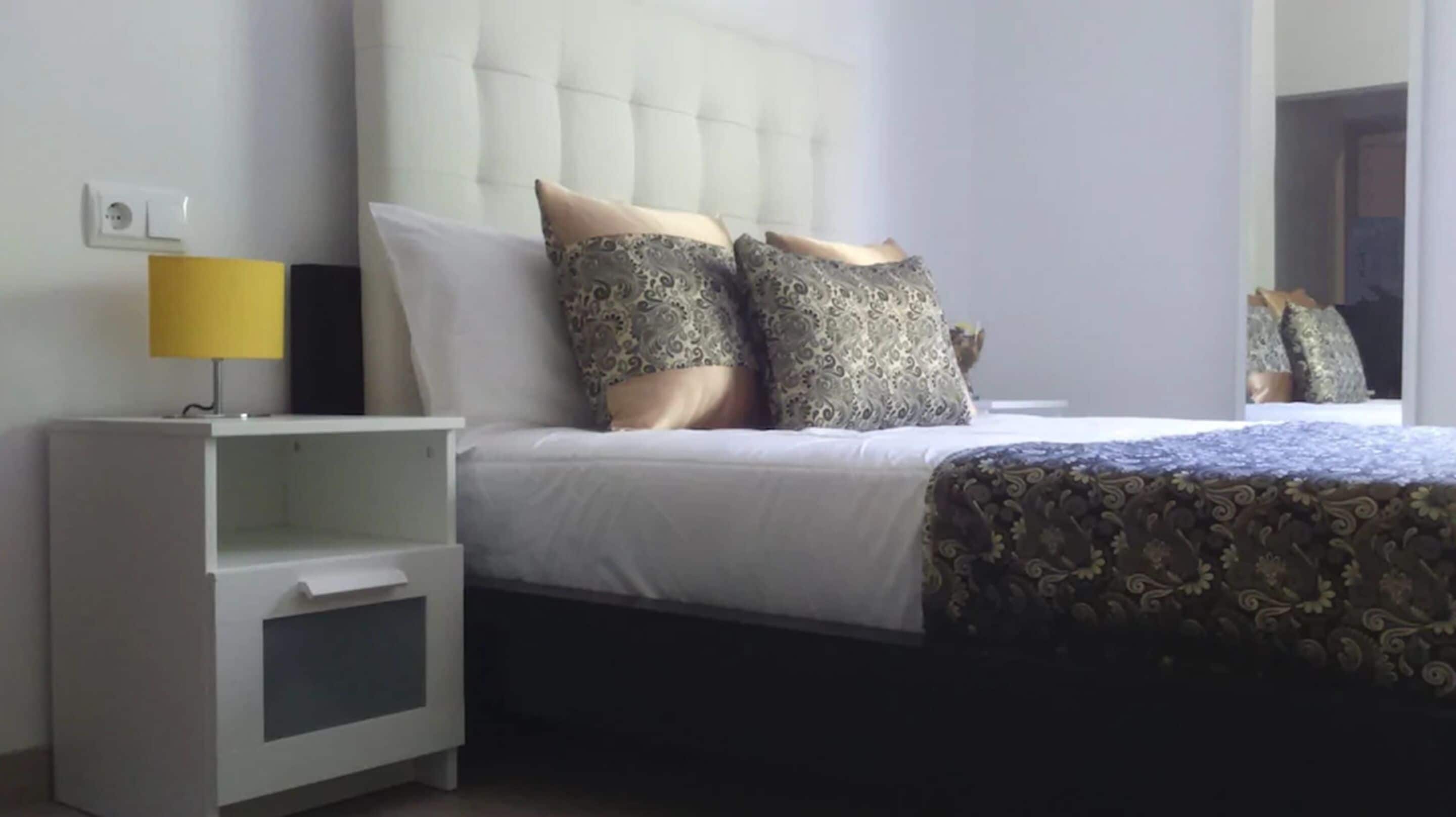 Une chambre d’hôtel avec un lit, une table de chevet et une lampe.