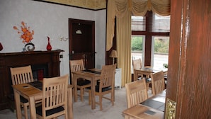 A dining room with wooden furniture, a fireplace, and a view through large windows. - Westview (Perth)