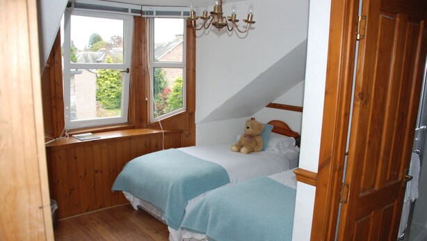 A bedroom with two beds, wooden flooring, a window, and a chandelier. - Westview (Perth)