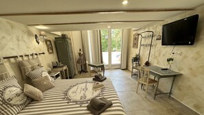 A bedroom with a bed, a desk, a chair, and a TV.