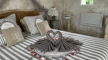 A neatly made bed with striped bedding, decorative pillows, and a swan-shaped towel arrangement.
