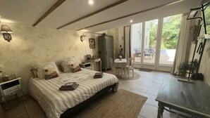 A bedroom with a large bed, bedside tables, a desk, and a view of the outside through a glass door.