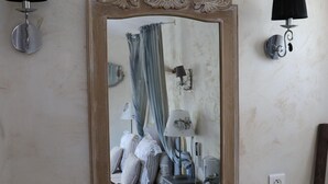 A bathroom with a large mirror, two wall-mounted lamps, a sink with a brass faucet, and a towel rack with a towel.