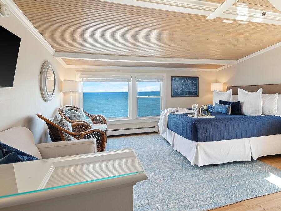 Quarto com uma cama grande, vista para o mar, móveis de vime e design de teto moderno.