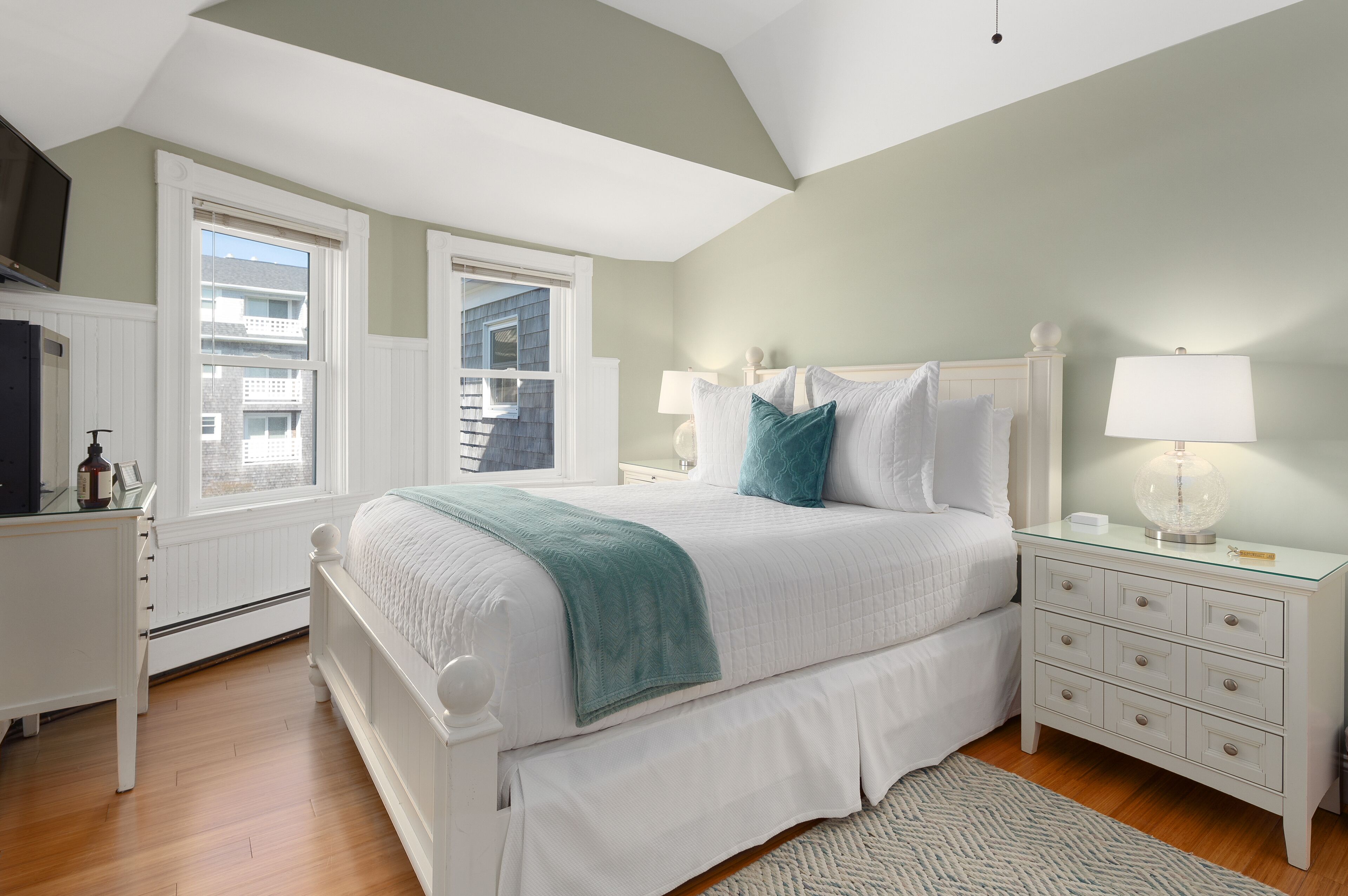 A bedroom with a bed, nightstands, a dresser, and a window.
