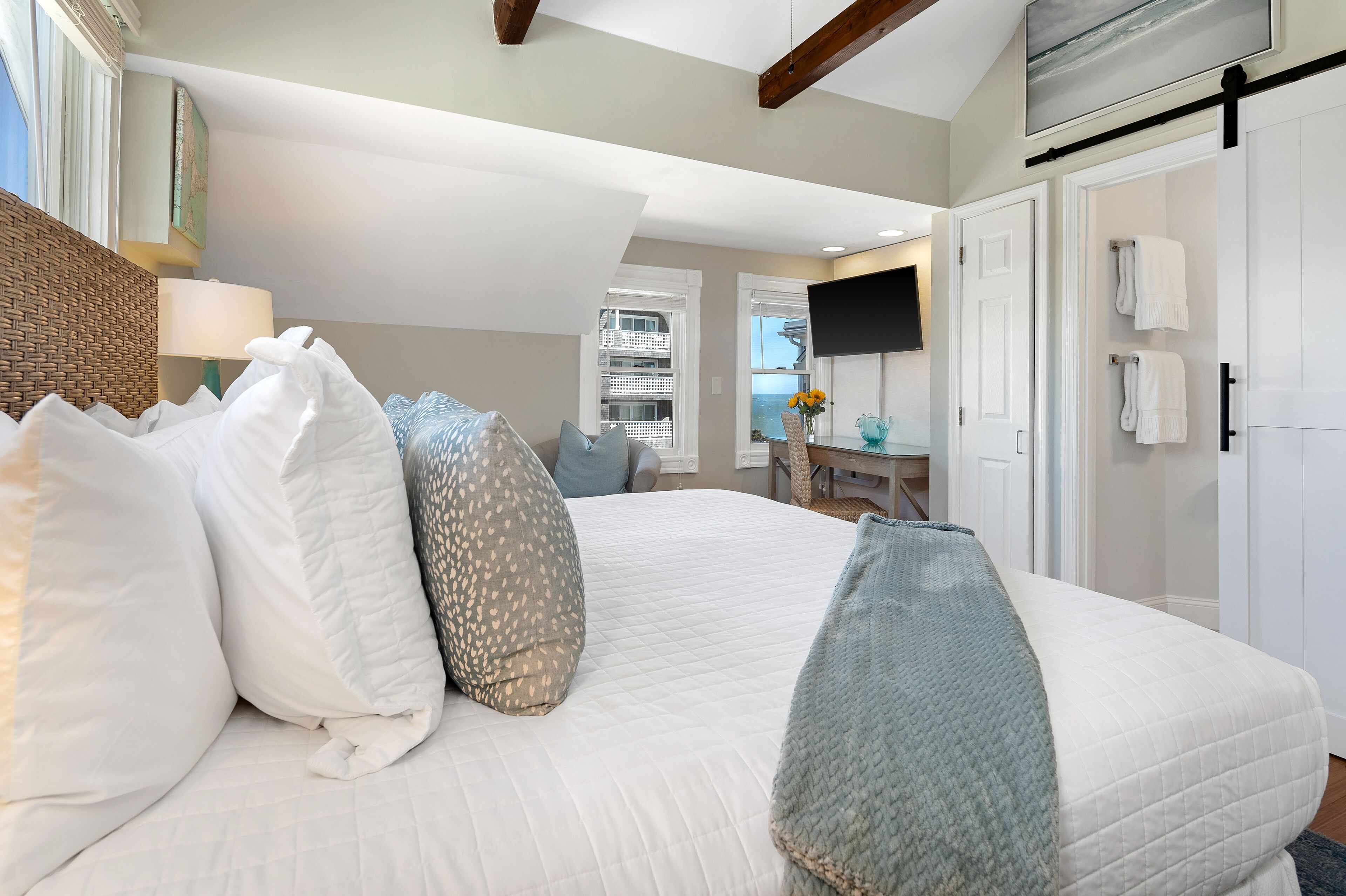A bedroom with a large bed, a desk, and a TV.