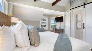 A bedroom with a large bed, a desk, and a TV.