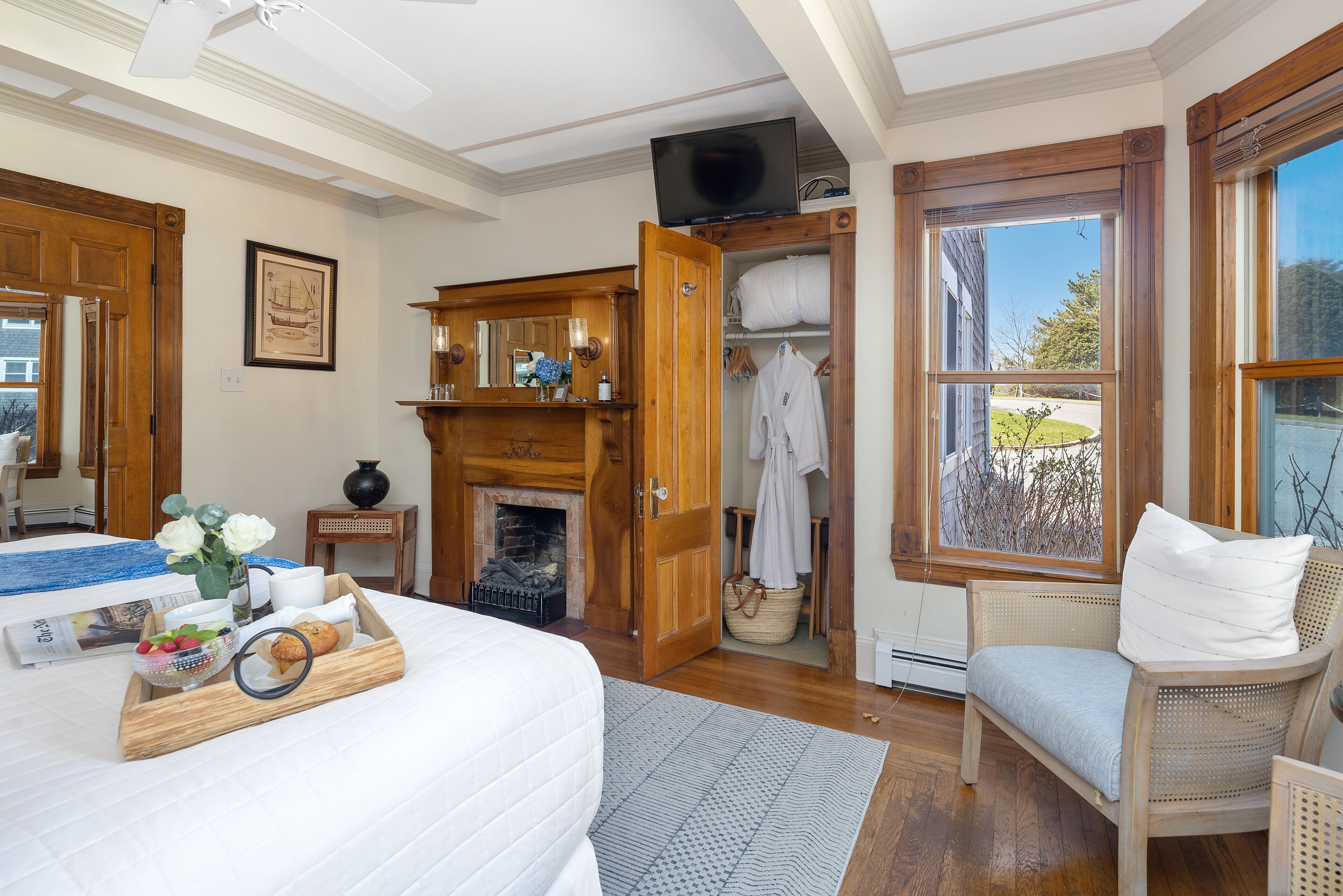 Un dormitorio con cama, cómoda de madera, chimenea, armario y ventana con vistas.
