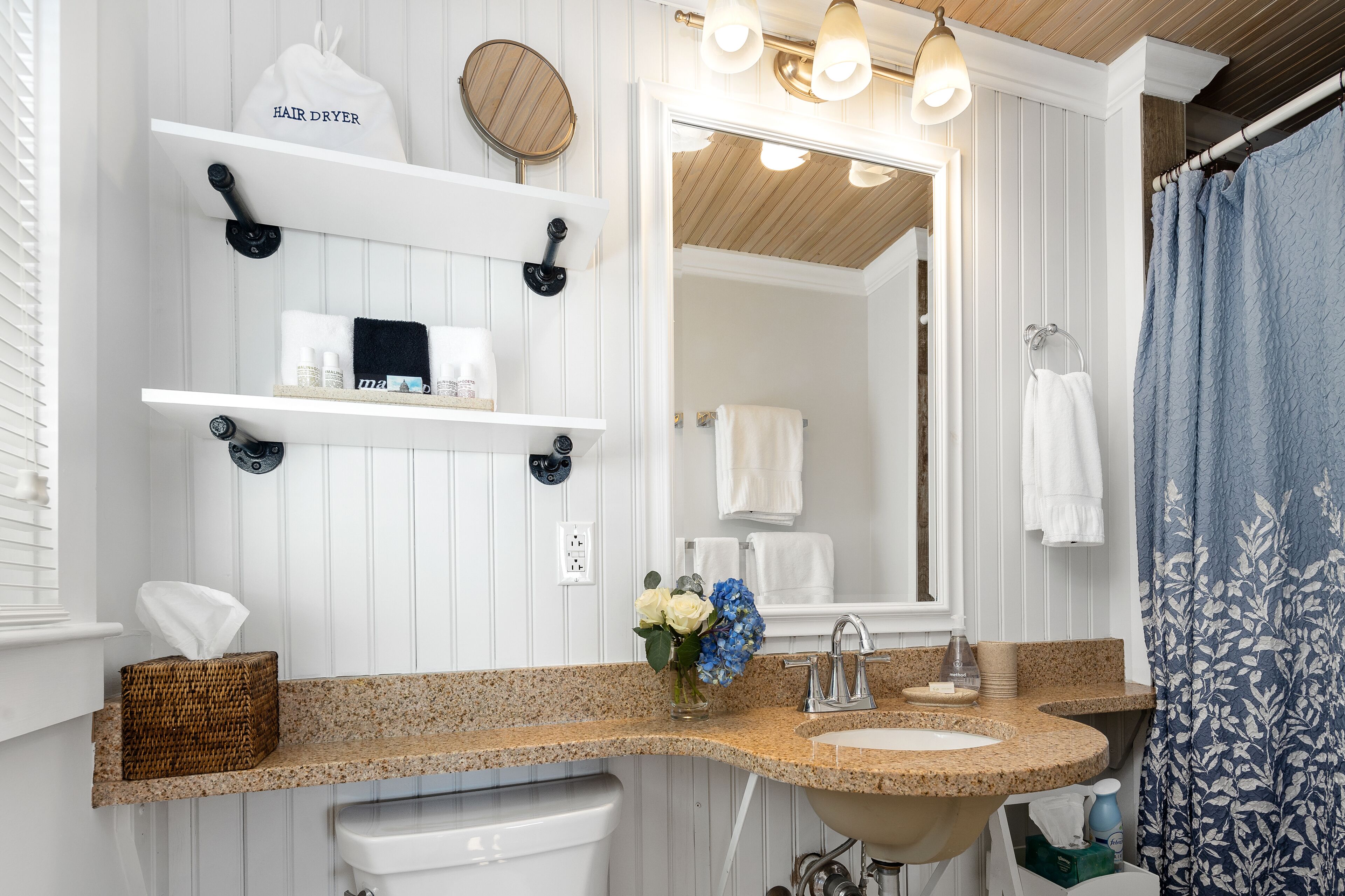 A bathroom with a granite countertop, a sink, a mirror, and a towel rack.