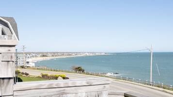A coastal road with a beach view, a wooden fence, and a clear sky.