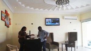 A reception area with a TV screen, a reception desk, and seating. - Lakeem Suites Adebola (Lagos)