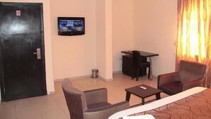 A living room with a television, a sofa, a coffee table, and a dining table. - Lakeem Suites Adebola (Lagos)