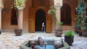 A courtyard with a fountain, potted plants, and a tiled floor. - Riad BenSaid (Marrakech)