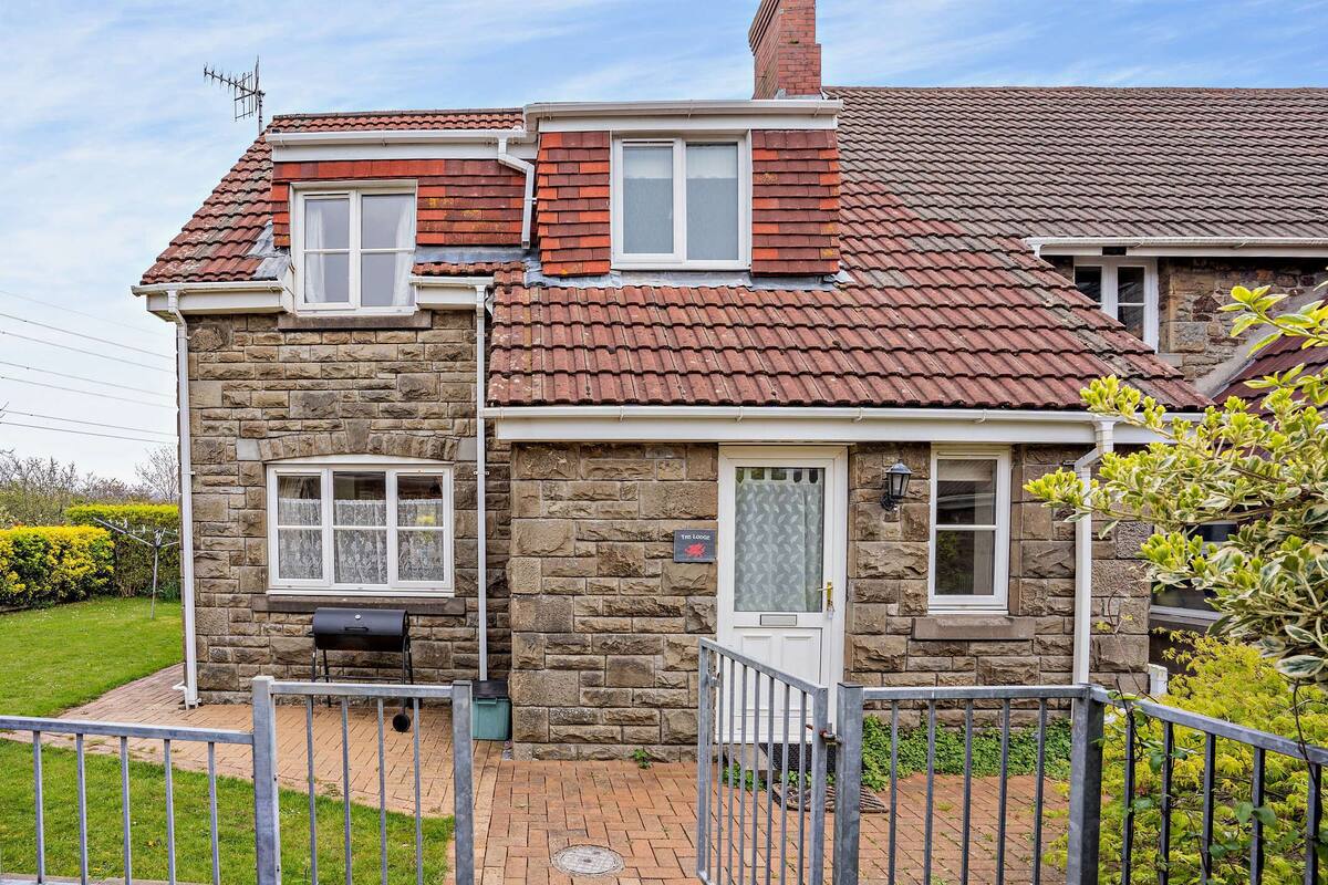 A stone house with a red-tiled roof, a front door, and a small window.