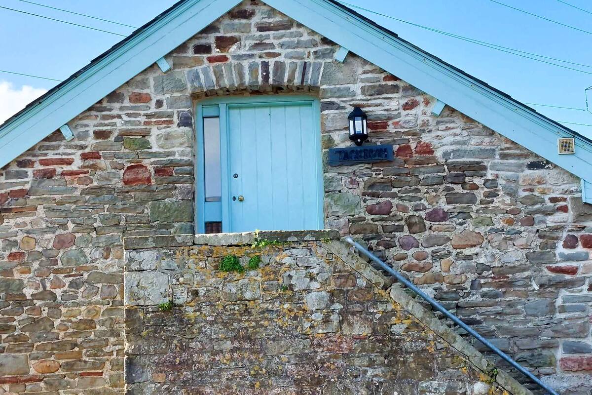 A stone building with a blue door and a sign that reads "TACHSROOM."