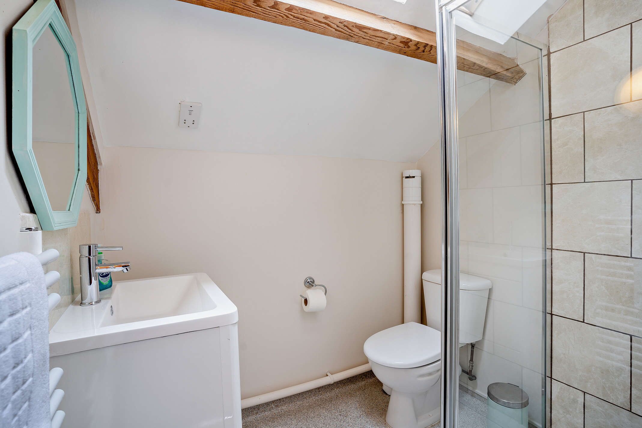 Une salle de bain avec un lavabo, des toilettes et une douche, le tout de couleur blanche.