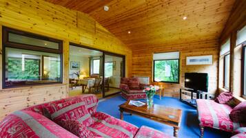 Relax in a spacious room with a high ceiling, featuring a sofa set, coffee table, and wall-mounted TV.
