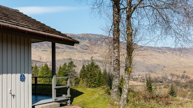 En stuga med en träveranda och utsikt över bergen.