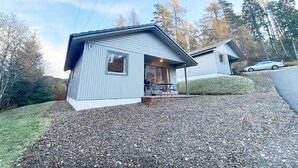 Une maison à deux étages avec une allée en gravier et une voiture garée dans la rue.