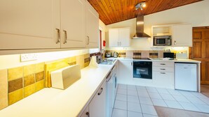 Une cuisine moderne avec des armoires blanches, un plafond en bois et un mur recouvert de carreaux.