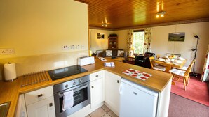 Une cuisine compacte équipée d’une cuisinière, d’un four et d’un réfrigérateur, un coin repas avec une table et des chaises, et un espace salon confortable avec un canapé.