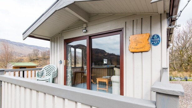 Ein überdachter Außenbereich mit Holzterrasse, einer Glastür zum Innenbereich und einem Schild, das ein schottisches Restaurant anzeigt.