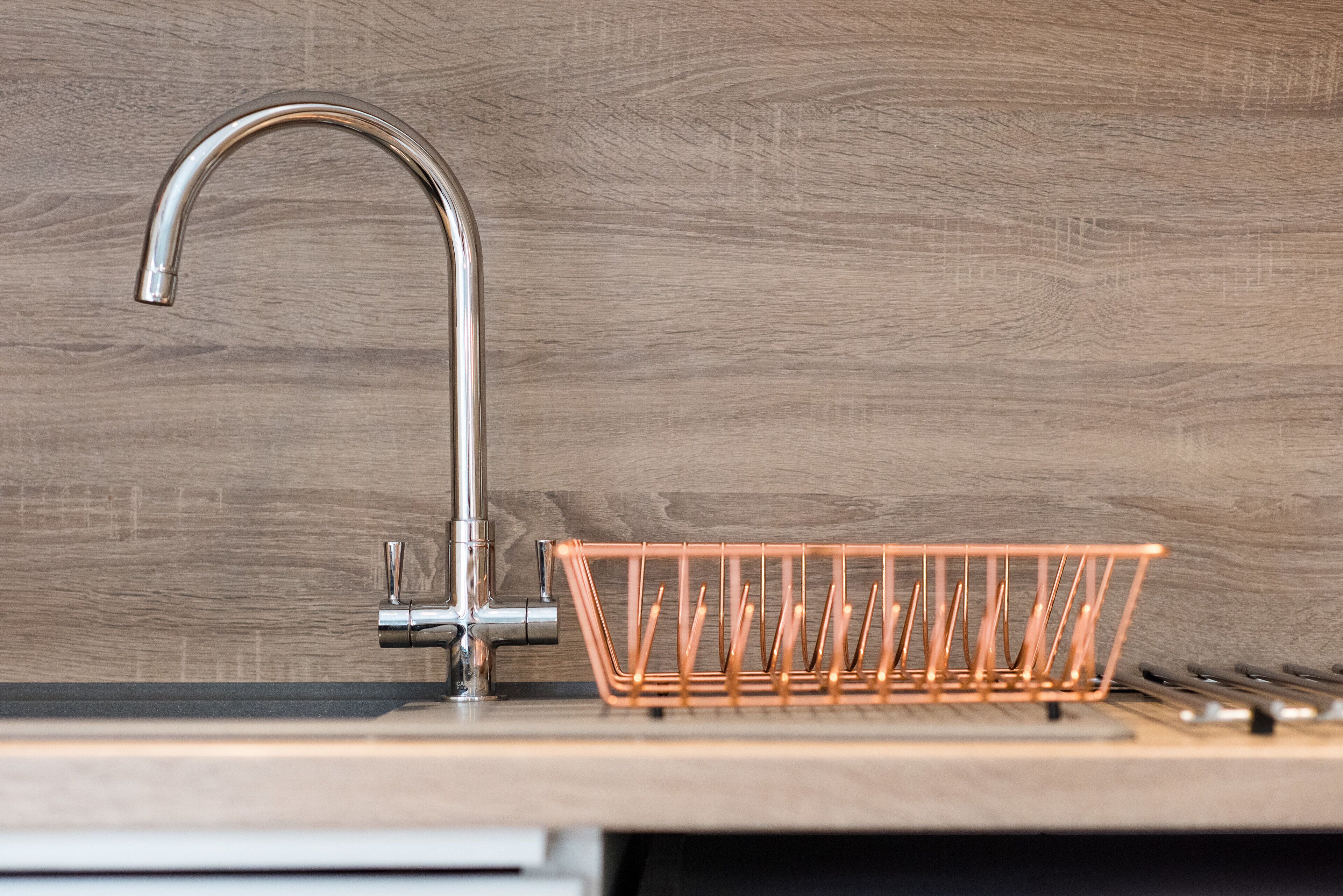 A kitchen sink with a copper drain strainer and a modern faucet.
