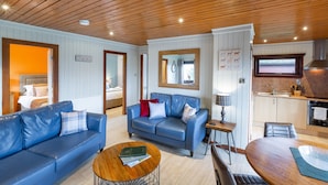 Ein gemütliches Wohnzimmer mit einem blauen Ledersofa, einem Holztisch und einer Küchenzeile mit Herd und Spüle.