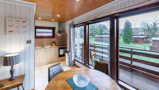 Eine moderne Küche mit Holzboden, ein Essbereich mit Tisch und Stühlen sowie ein großes Fenster mit Blick auf einen Garten.