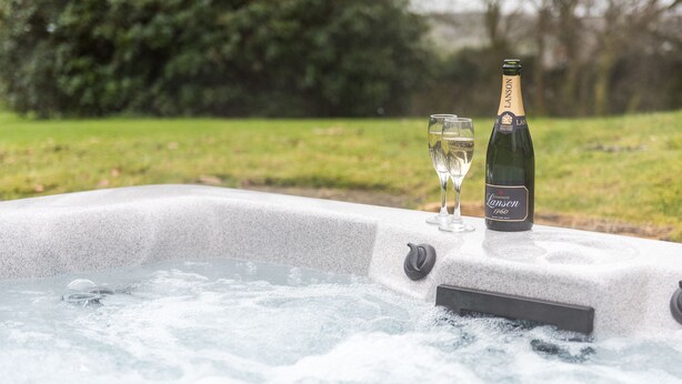 Un jacuzzi con una botella de champán y una copa.
