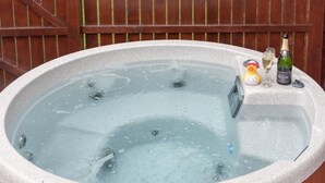 A hot tub with a wooden fence in the background. - Birch Lodge 13 with Hot Tub (Newton Stewart)