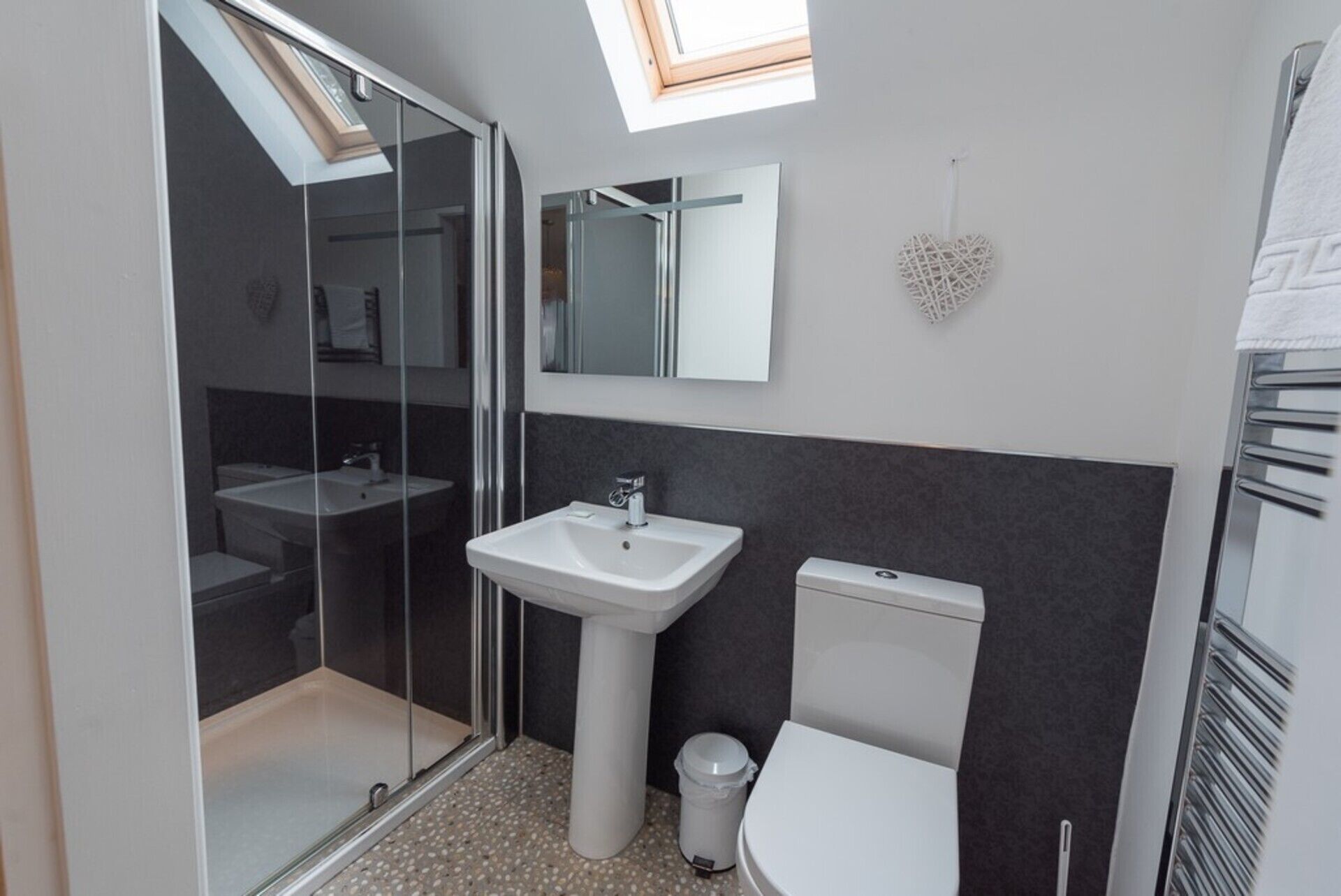 Une salle de bain moderne avec une douche à parois de verre, un lavabo sur colonne, des toilettes et un meuble-lavabo avec un miroir.